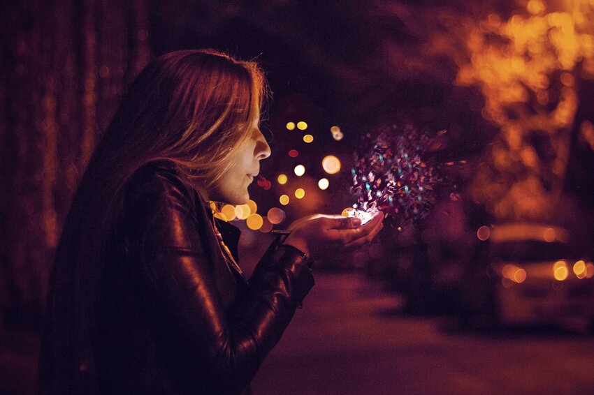 Woman blowing confetti into the air during the night